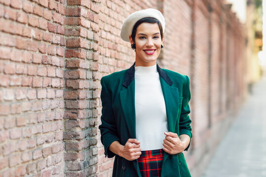 Portrait of smiling fashionable young woman at a brick wall