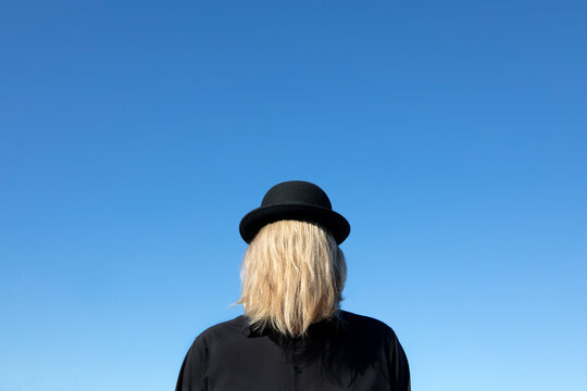 Blond hair covering man's face wearing bowler hat