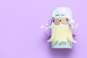 Figure of cute doll made of cardboard tube for toilet paper on color background