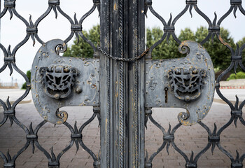 Lock, chain and handles in the shape of fairy-tale animal heads on the gate grating of the medieval...