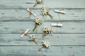 Beautiful gypsophila boutonnieres and wedding invitations on color wooden background