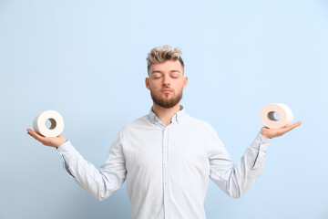Meditating young man with toilet paper on color background