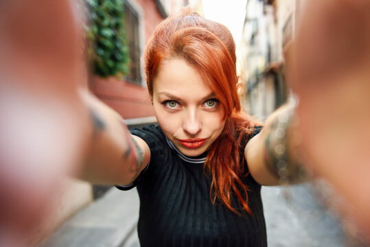 Selfie portrait of red-haired woman in the city