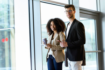 Portrait of two young business partners standing in a hallway