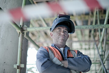 Male construction worker with arms crossed at site