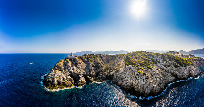 Spain, Mallorca, Cala Ratjada, Helicopter view of sun shining over coastal cliffs and Far de Capdepera lighthouse in summer