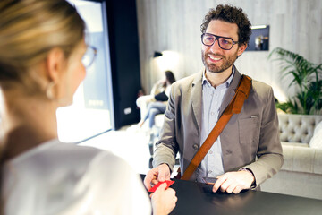 Smiling businessman handing over credit card at reception