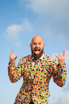 Portrait of bald man with beard  wearing suit with colourful polka-dots sticking out tongue