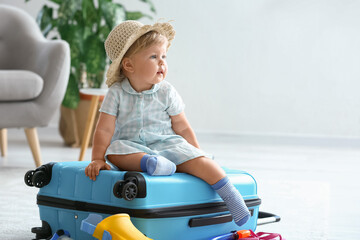 Cute baby girl with suitcase at home