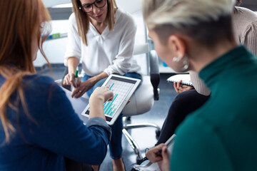 Businesswomen using charts on digital tablet during meeting in an office