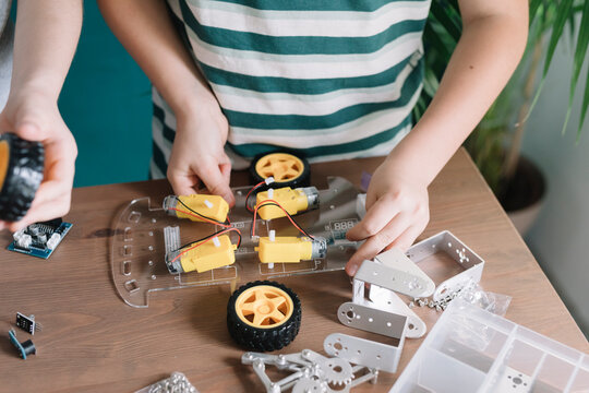 Close-up of siblings making robot on table at home