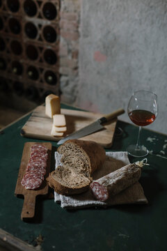 Fresh salami sausage with homemade bread and wine on table in cellar