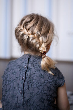 Girl with braided blond hair sitting at home