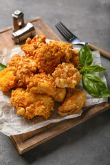Board with tasty popcorn chicken on grey background