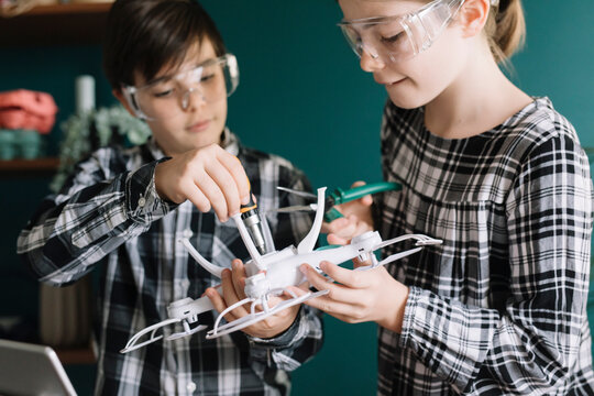 Close-up of siblings making drone at home