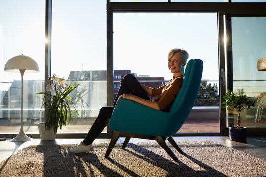Portrait of smiling woman sitting in armchair in sunlight