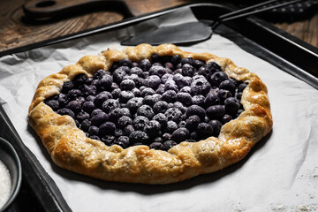 Baking tray with tasty blueberry galette on table, closeup