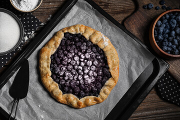 Baking tray with tasty blueberry galette on wooden background