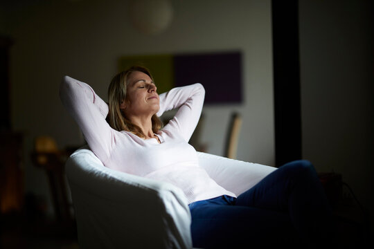 Woman sitting at home, relaxing in arm chair