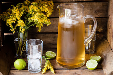 Jug and glass of iced goldenrod tea with limes
