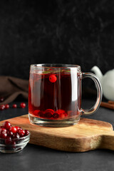 Glass cup of hot cranberry tea on dark background