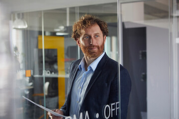 Portrait of confident businessman holding papers in office