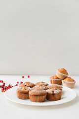Plate with delicious cranberry muffins on white background