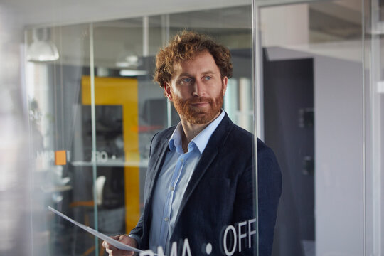 Portrait of confident businessman holding papers in office
