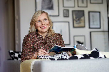Smiling blond woman relaxing at home sitting on couch