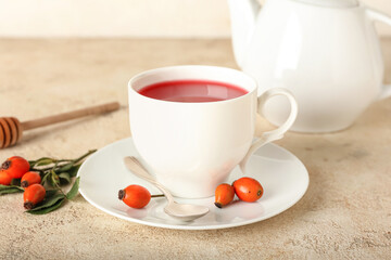 Cup of tasty rose hip tea on light background