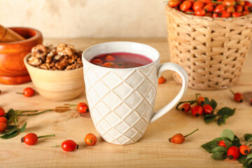 Cup of tasty rose hip tea and berries on table