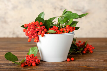 Bowl with ripe rowan berries on wooden table