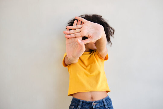 Woman showing stop gesture while standing against white wall