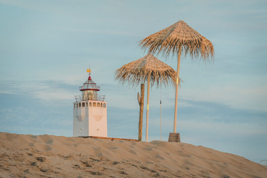 Netherlands, South Holland, Noordwijk, lighthouse and sun shades on sandy beach