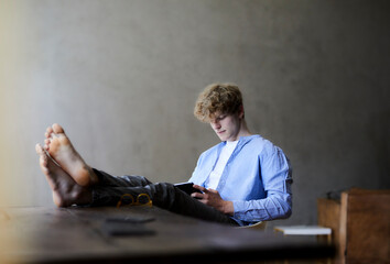 Young man with feet on table using digital tablet