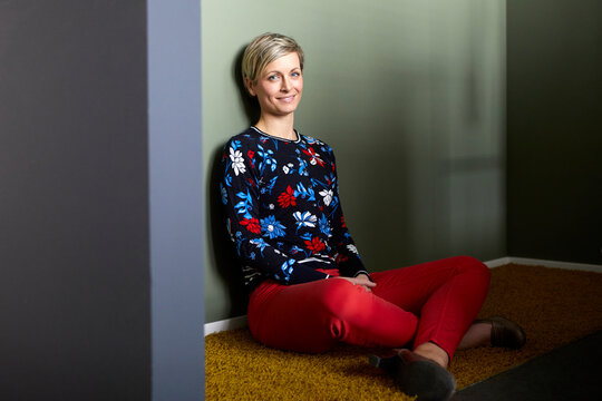 Portrait of a smiling blond woman sitting on carpet