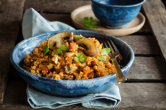 Bowl of ready-to-eat fried millet with mushrooms and parsley