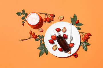 Composition with cosmetic products, rose hip berries and leaves on color background
