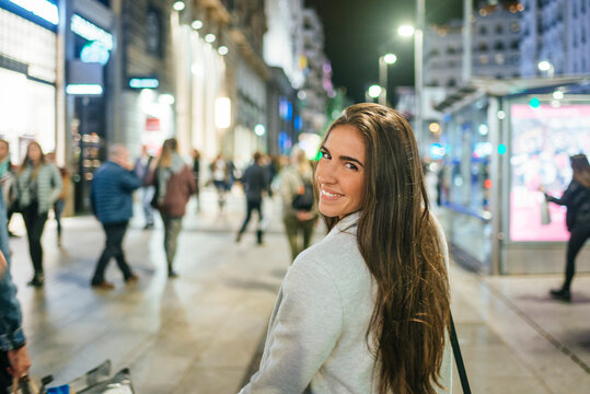 Portrait of a smiling woman walking down shopping street at night