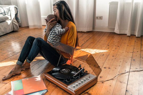Mother with baby sitting on the floor at home with a record player