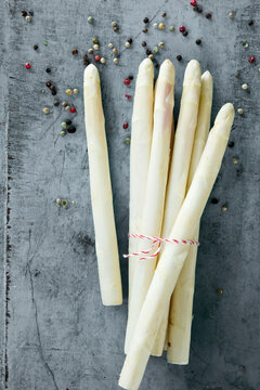 Studio shot of peppercorns and bundle of peeled white asparagus