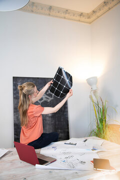 Woman sitting on desk in office looking at printout