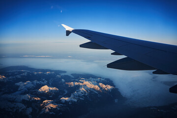 France, Auvergne-Rhone-Alpes, Wing of Airbus A321 flying over European Alps and Lake Geneva at dawn