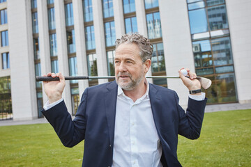 Mature businessman with golf club in the city