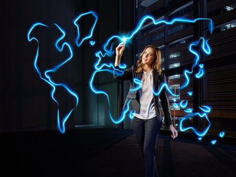 Businesswoman painting a worldmap with light, pointing on Europe