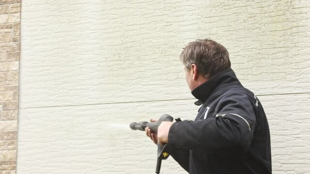 Man cleaning walls with high pressure power washer. Washing cladding walls house. High quality 4k footage