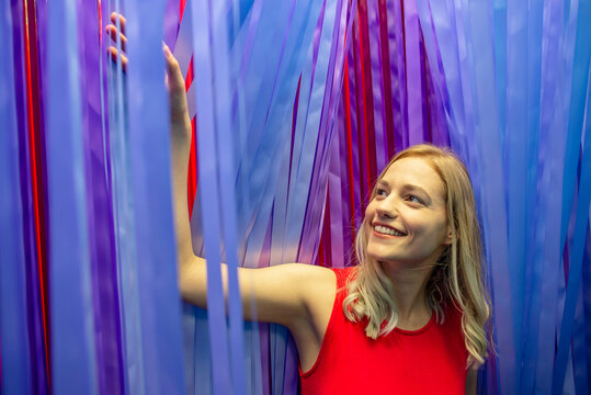 Smiling beautiful woman standing amidst hanging ribbons