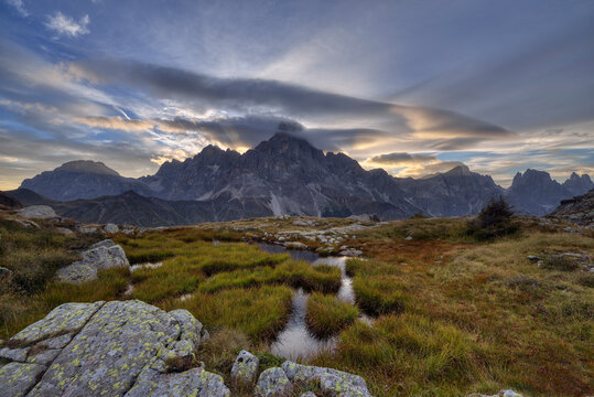 Italy, Dolomites, Passo Rolle, Trentino, Pale di San Martino Mountain group with mountain peak Cimon della Pala with small pond at sunrise