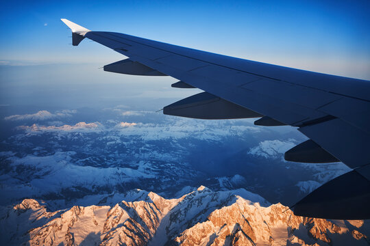 France, Auvergne-Rhone-Alpes, Wing of Airbus A321 flying over European Alps and Lake Geneva at dawn