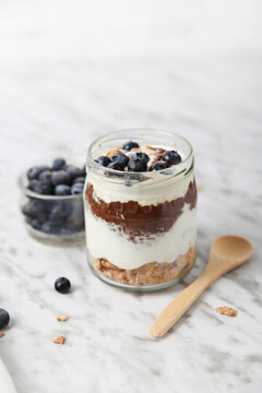 Jar of chia pudding parfait with chocolate and yoghurt with blueberries and granola